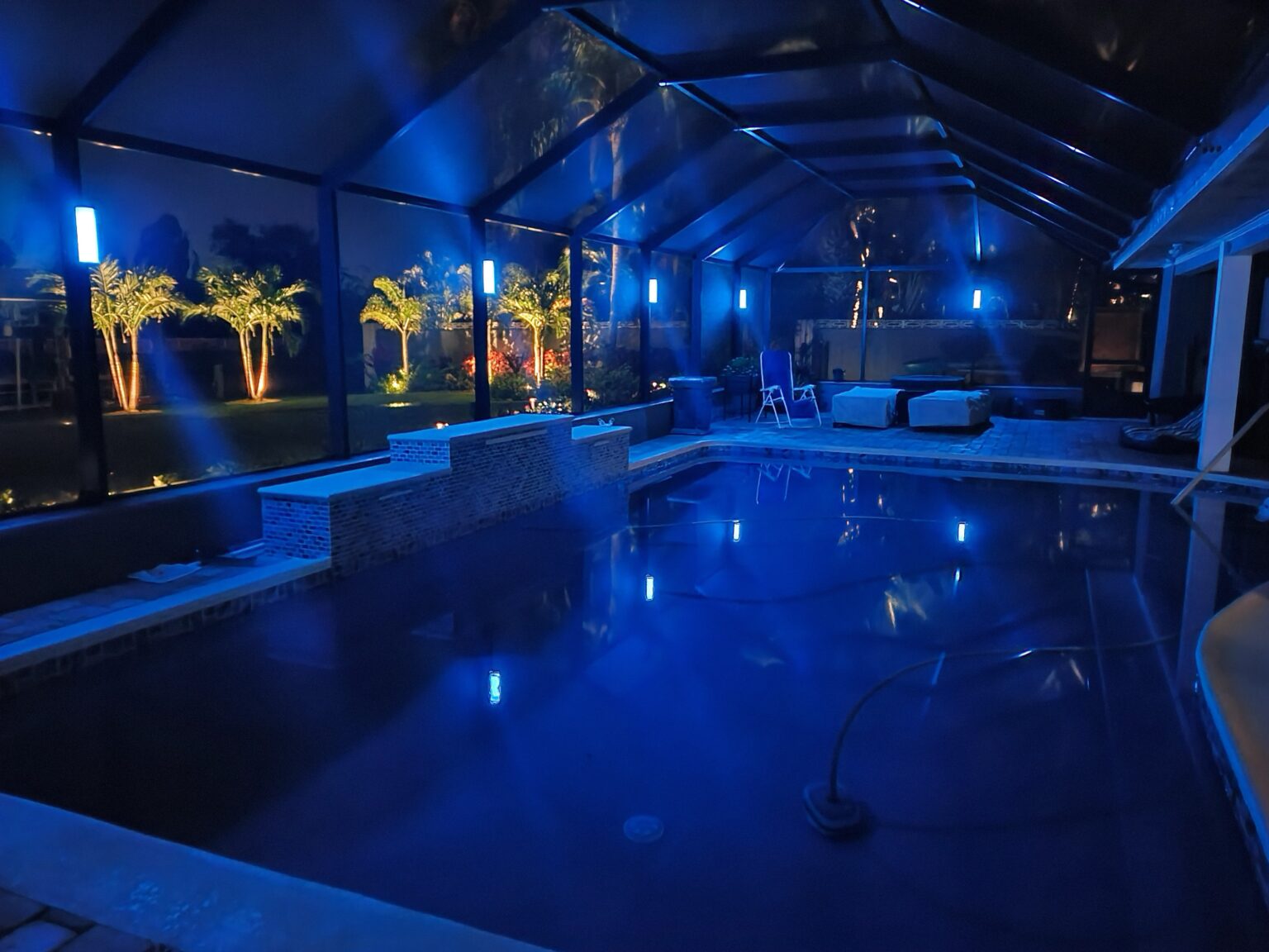 Pool and patio illuminated at night with custom landscape lighting