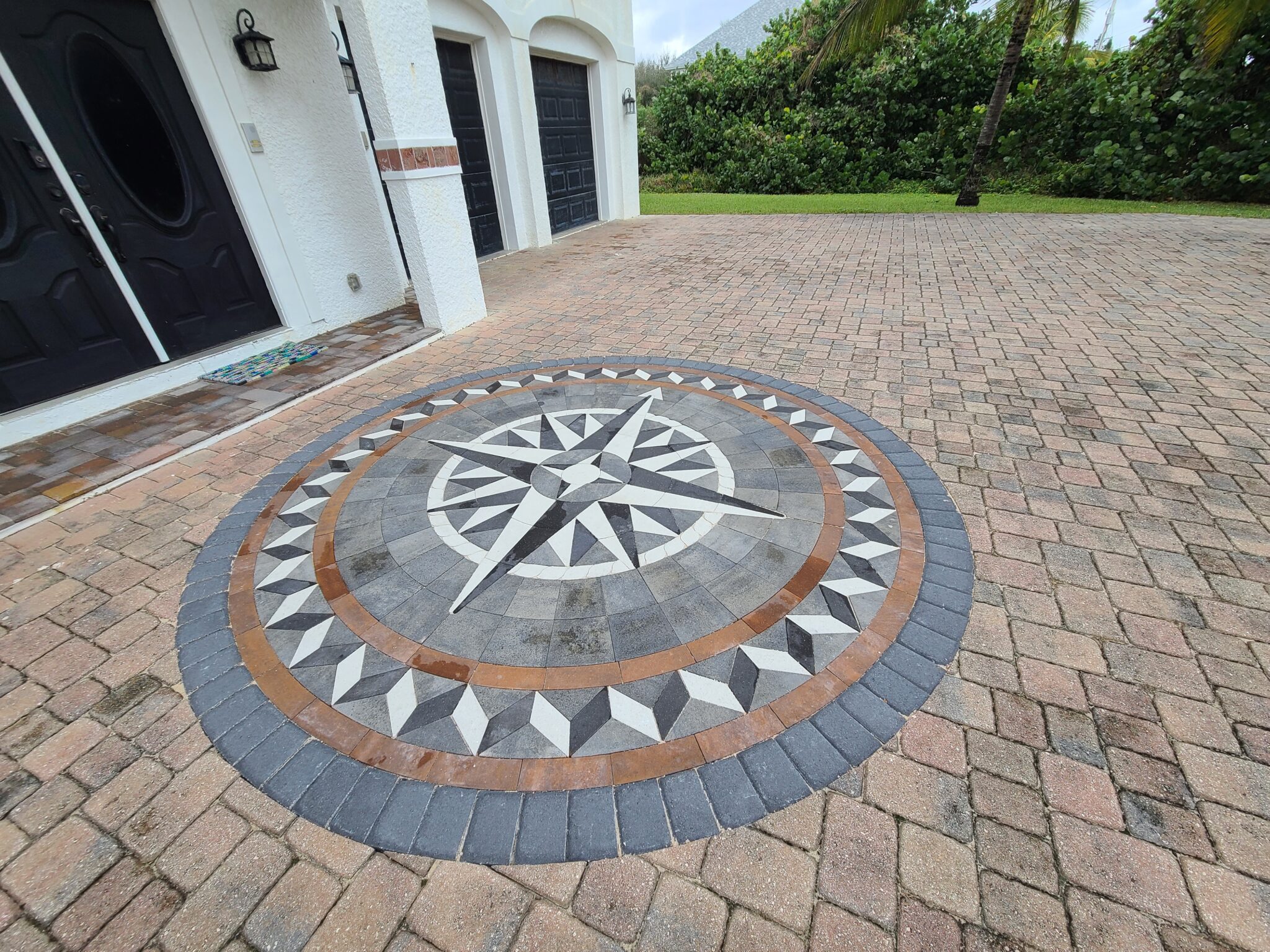 Custom compass rose paver inlay set into a brick paver driveway