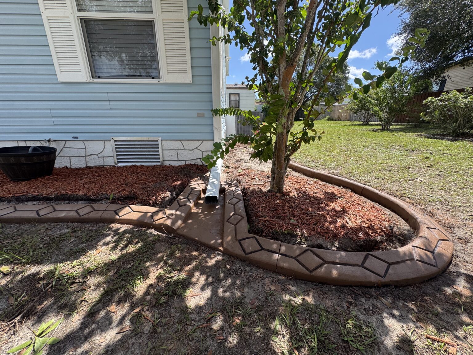 Decorative concrete landscape curbing around a mulched tree bed