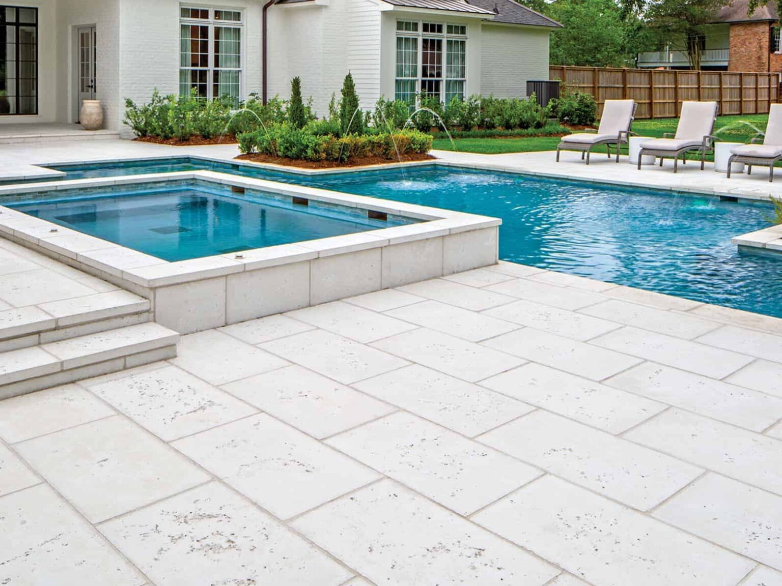 White paver pool deck surrounding an in-ground pool